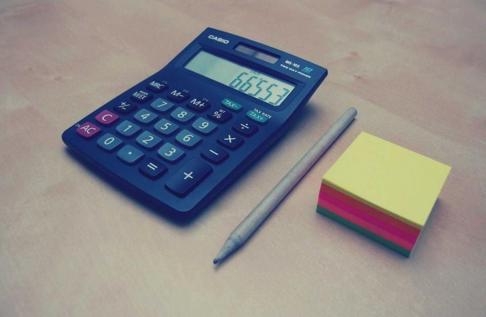 机の上に置かれた電卓と、数字の並んだ書類